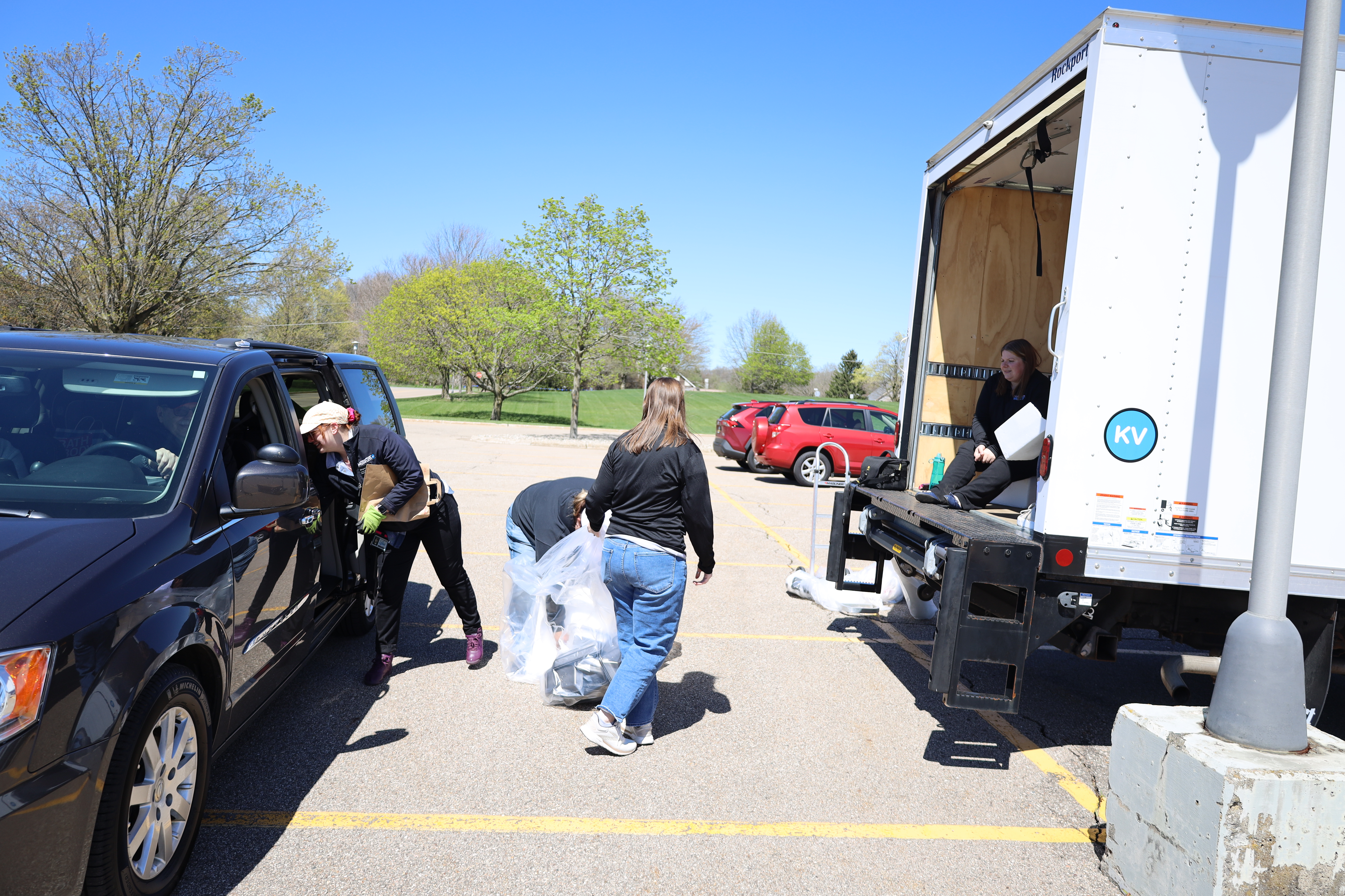 Image of people unloading a bag of items from their vehicle into a truck.